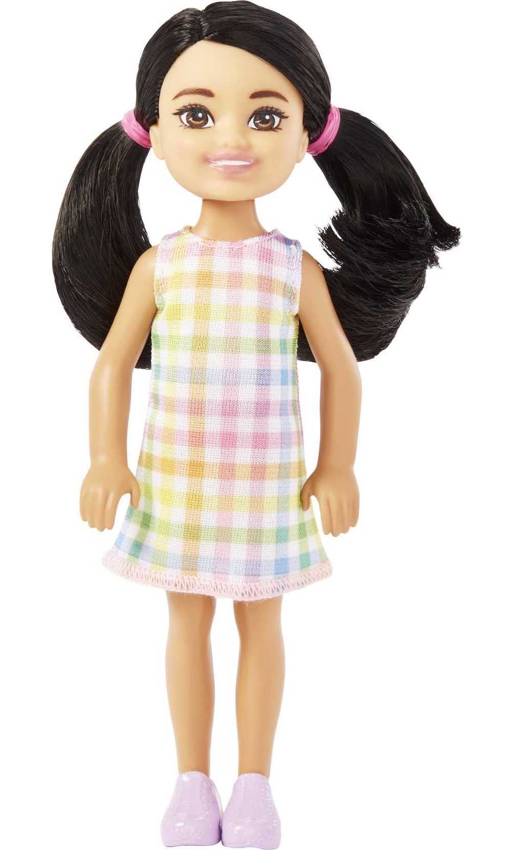 A small doll with black braids and brown eyes wearing a detachable plaid dress and pink shoes